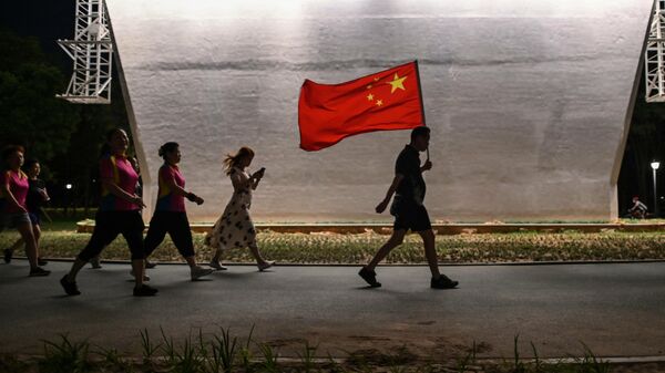 Мужчина с флагом Китая идет по парку в Ухани 