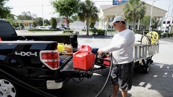 Мужчина наполняет канистры топливом после кибератаки на трубопровод компании Colonial Pipeline в Тампе, Флорида, США