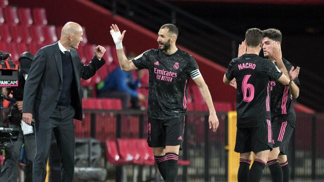 Real Madrid's French forward Karim Benzema celebrates with Real Madrid's French coach Zinedine Zidane after scoring a goal during the Spanish league football match Granada FC against Real Madrid CF at the Nuevo Los Carmenes stadium in Granada on May 13, 2021. (Photo by JORGE GUERRERO / AFP)