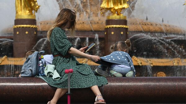 Женщина с ребенком у фонтана Дружба народов на ВДНХ в Москве