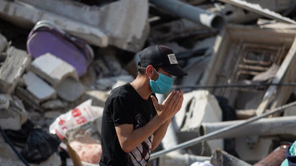 Палестинец молится среди обломков здания, разрушенного в результате удара израильских сил по сектору Газа