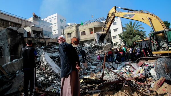 Спасатели разбирают обломки, разрушенного в результате бомбардировки здания, в секторе Газа