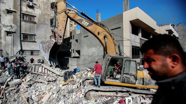 Спасатели разбирают завалы разрушенного в результате бомбардировки здания в секторе Газа