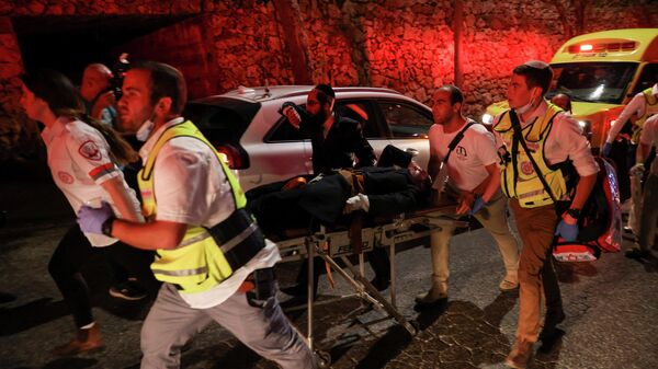 Cпасатели несут раненного во время обрушения трибуны синагоги в Гиват-Зееве, Израиль