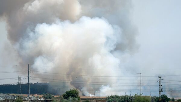 Пожар в поле, вызванный попаданием ракеты,  возле кибуца Гварам на юге Израиля
