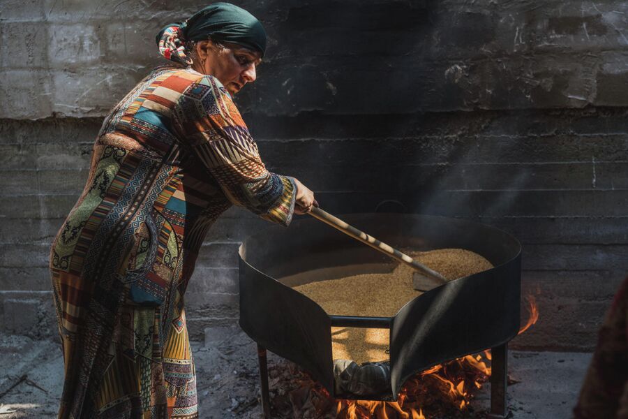 Женщина поджаривает семена льна для приготовления урбеча на водяной мельнице. Село Рахата, Ботлихская долина