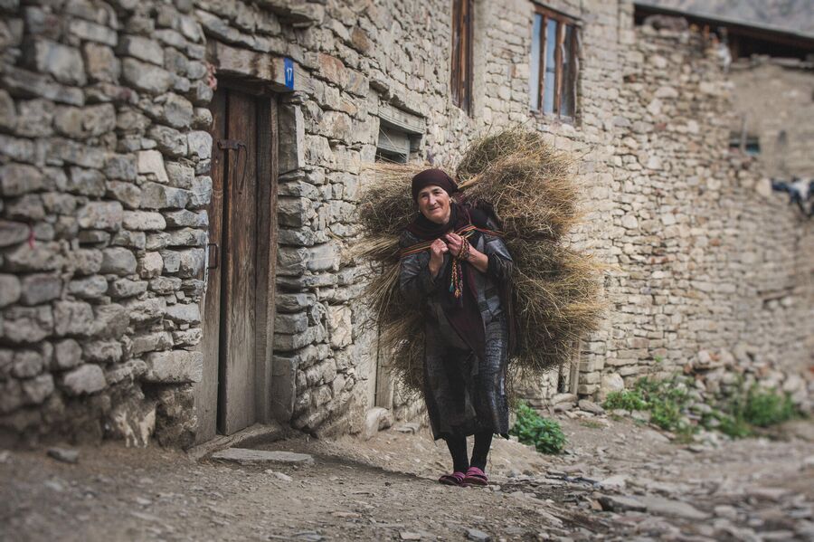 Женщина несет стено через село Корода