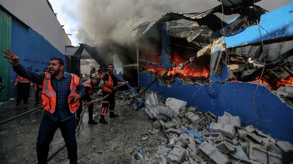 Члены Палестинской гражданской обороны тушат пожар на заводе по производству пенопласта в секторе Газа