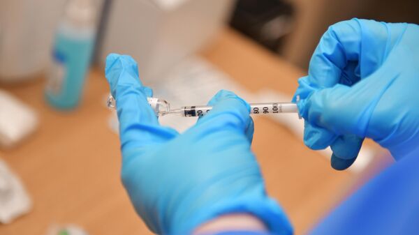 Медик набирает в шприц российский препарат Sputnik V от коронавирусной инфекции COVID-19