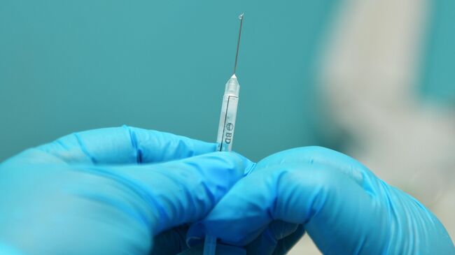 Медик готовит шприц с вакциной от коронавирусной инфекции COVID-19