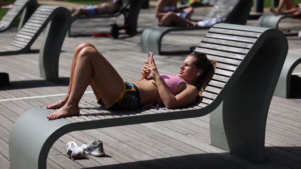 Девушка загорает на ВДНХ в Москве в жаркую погоду