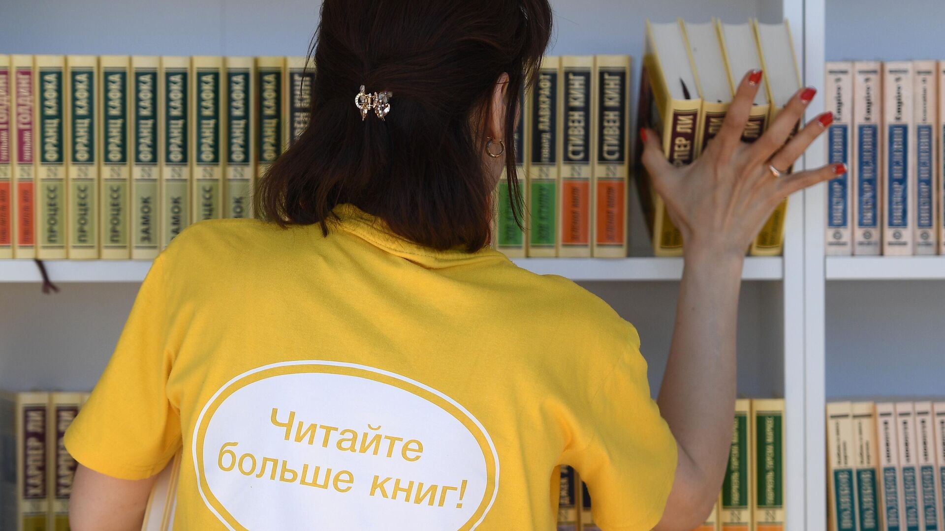 Женщина расставляет книги на полках на ежегодном российском книжном фестивале на Красной площади - РИА Новости, 1920, 24.04.2023