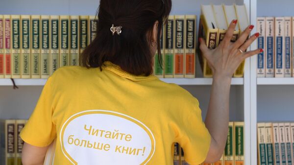 Женщина расставляет книги на полках на ежегодном российском книжном фестивале на Красной площади