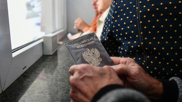 Пассажир держит в руках паспорт на железнодорожном вокзале