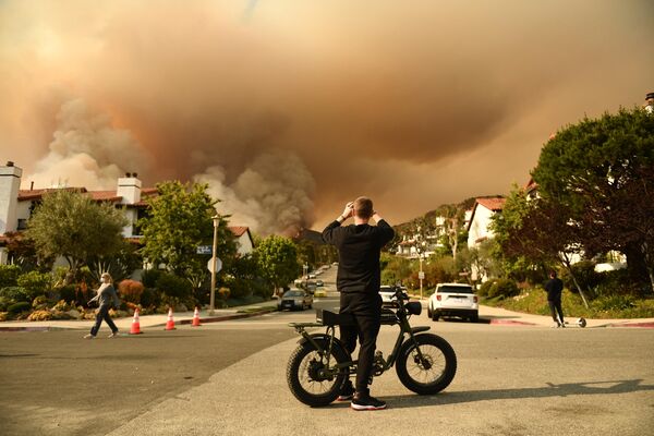 Мужчина фотографирует дым от пожара в государственном парке Топанга к северо-западу от Лос-Анджелеса