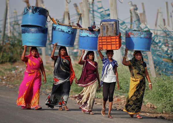 Женщины несут вещи со своих рабочих мест, разрушенных циклоном Тауктае в Индии 