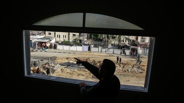 Житель Газы смотрит в окно дома, разбитое в результате бомбардировки ЦАХАЛ