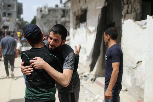 Палестинцы обнимаются после возвращения в свои разрушенные дома в Бейт-Хануне на севере сектора Газа