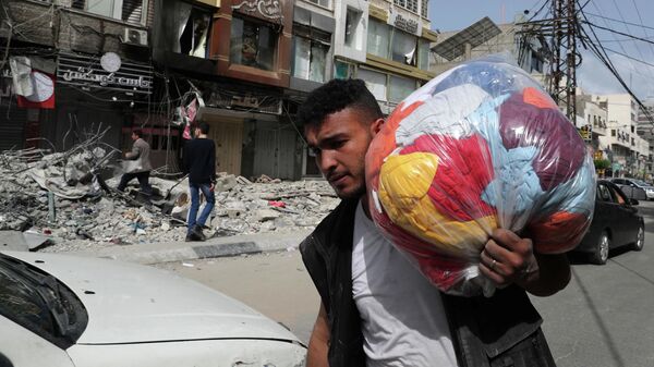 Палестинец проходит мимо разрушенных в результате бомбардировки зданий в секторе Газа, после объявления о прекращении огня между Израилем и ХАМАС