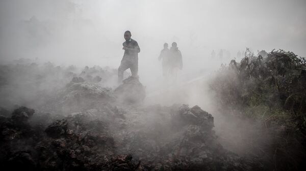 Мужчины идут мимо дымящейся лава после извержения вулкана Ньирагонго в Демократической республике Конго
