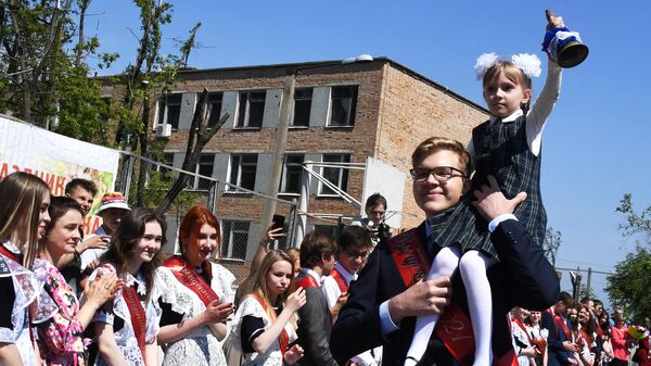 Выпускник несет школьницу с колокольчиком во время последнего звонка в гимназии №2 во Владивостоке