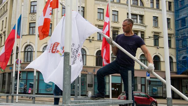 Мужчина снимает флаг Международной федерации хоккея в Риге