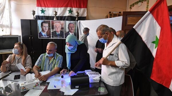 Люди на одном из избирательных участков Дамаска, где проходит голосование на выборах президента Сирии