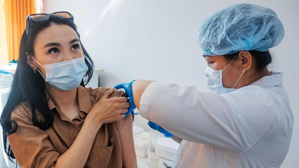 Медицинский сотрудник вакцинирует жительницу Якутска от Covid-19