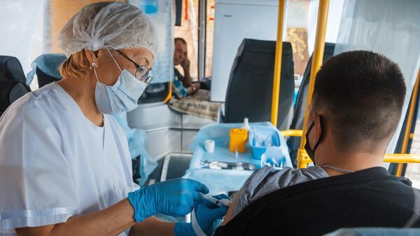 Медицинский сотрудник вакцинирует жителя Якутска от Covid-19 в мобильном пункте вакцинации