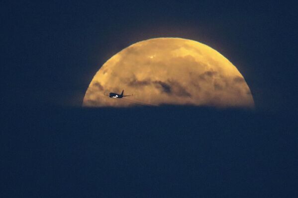 Самолет на фоне Луны в Санта-Моника, штат Калифорния