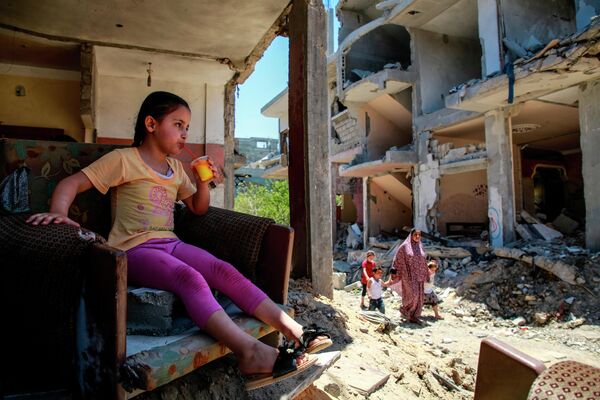 Девочка пьет сок в разрушенном доме на северо-востоке сектора Газа в городе Бейт-Ханун 