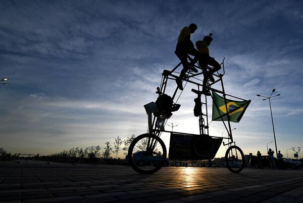 Бразильские футбольные фанаты катаются на самодельном трехметровом тандемном велосипеде возле Ростов-Арены накануне матча между Бразилией и Швейцарией во время чемпионата мира по футболу