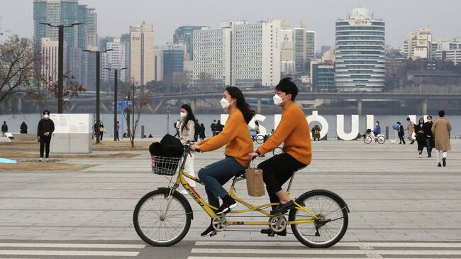 Пара катается на тандеме в парке в Сеуле, Южная Корея