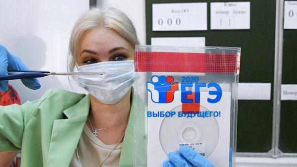 Учительница вскрывает конверт с диском, в котором содержатся задания для единого государственного экзамена по русскому языку, перед началом ЕГЭ по русскому языку