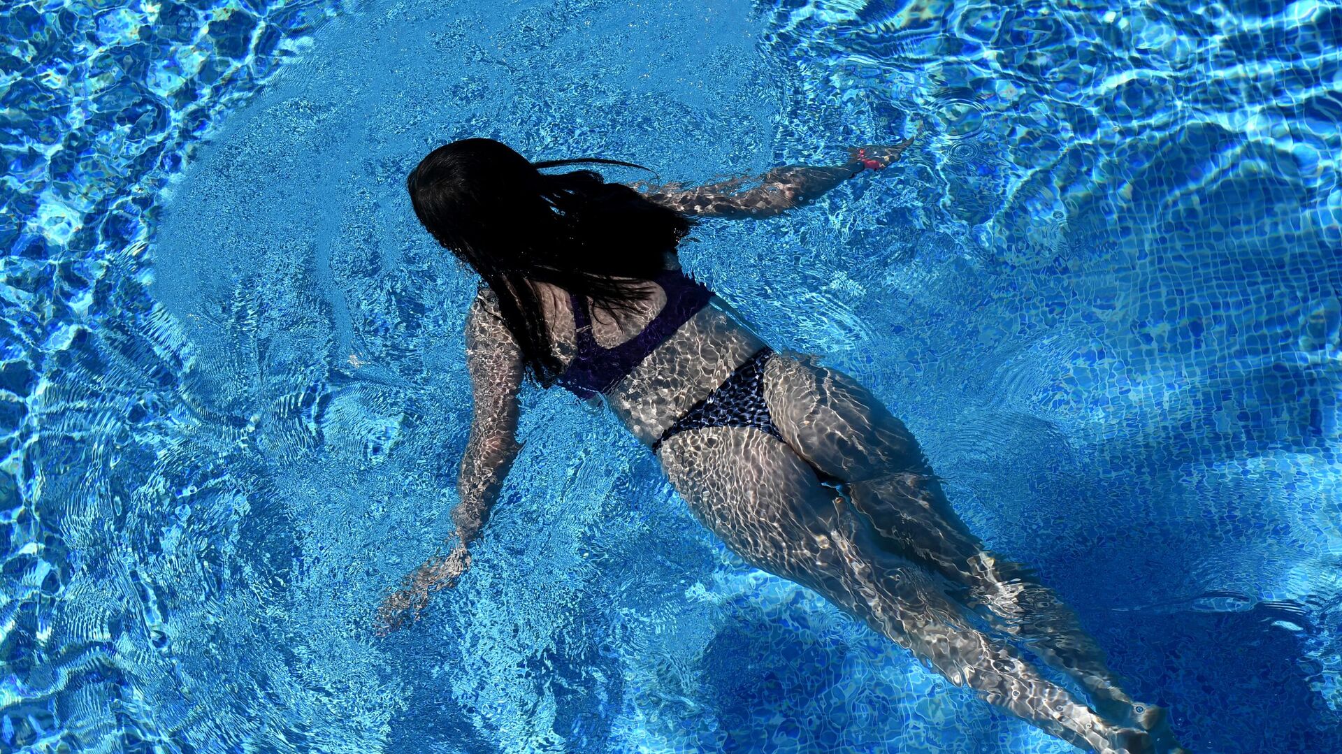 Девочка плавает в открытом бассейне в парке развлечений 