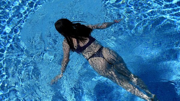 Девушка плавает в открытом бассейне в фанпарке Бобровый лог в Красноярске