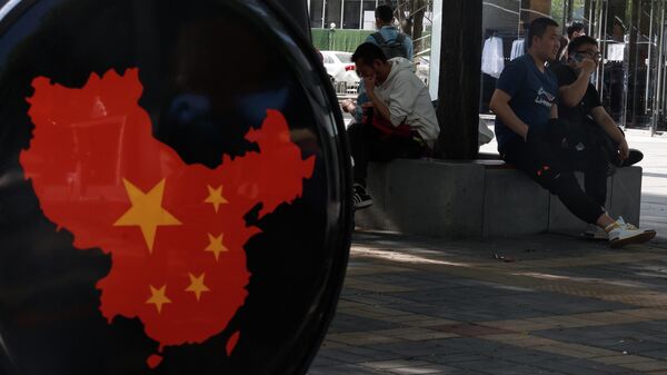 Жители отдыхают возле карты Китая в торговом районе Пекина