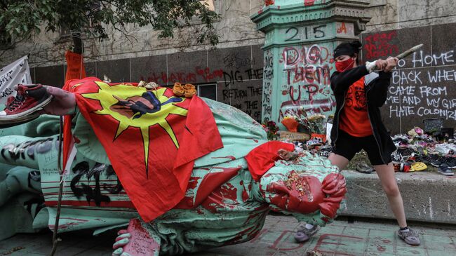 Участник акции протеста возле статуи Эгертону Райерсону в городе Камлупс, Канада