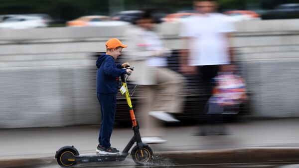 Мальчик едет на электросамокате в центре Москвы