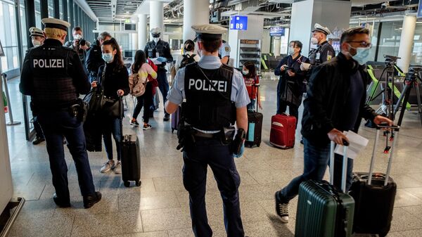 Сотрудники полиции проверяют наличие теста на коронавирус у прибывших пассажиров в аэропорту Франкфурта, Германия