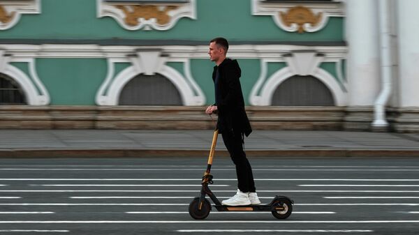Молодой человек едет на самокате по Дворцовой площади в Санкт-Петербурге