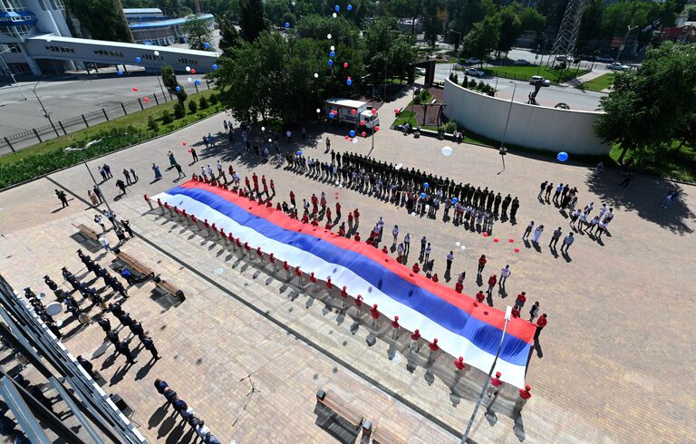 Военнослужащие Южного военного округа и волонтеры под музыку военного оркестра развернули 50-метровый государственный флаг России в честь празднования Дня России у здания Исторического парка Россия - моя история в Ростове - на - Дону.