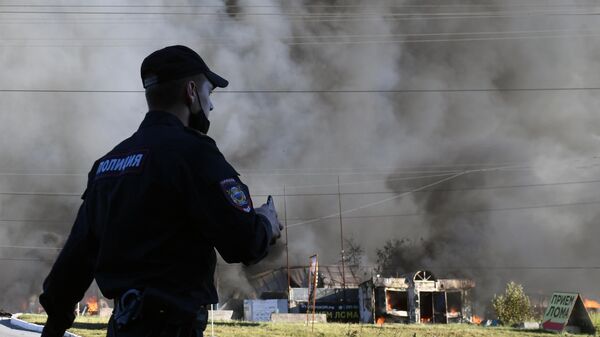 Сотрудник полиции у горящей автозаправки в Новосибирске