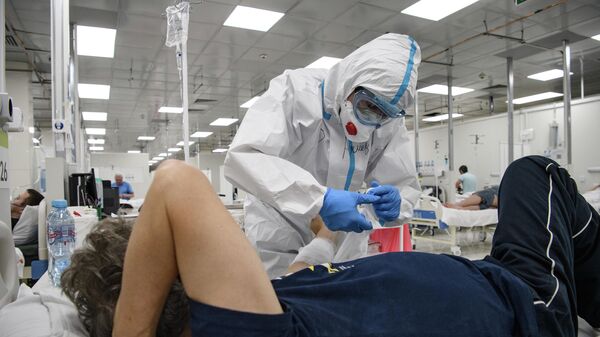 Врач оказывает помощь пациенту в резервном госпитале для лечения больных коронавирусом в АТЦ Москва
