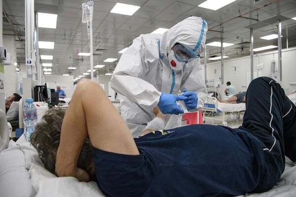 Врач оказывает помощь пациенту в резервном госпитале для лечения больных коронавирусом в АТЦ Москва