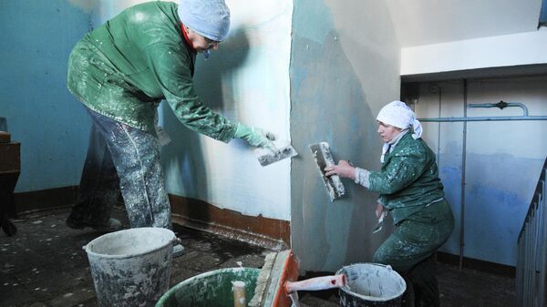 Маляры выравнивают стены во время ремонта лестничных пролетов подъезда жилого дома