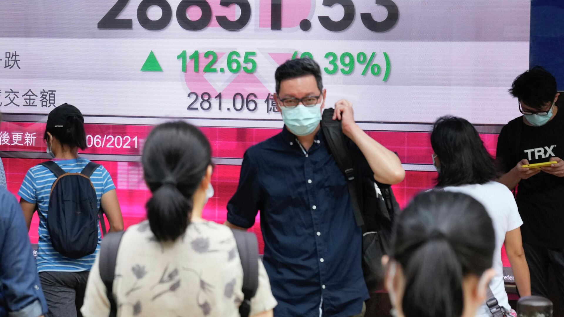 Люди в защитных масках проходят мимо табло с котировками ценных бумаг в Гонконге - РИА Новости, 1920, 16.06.2021