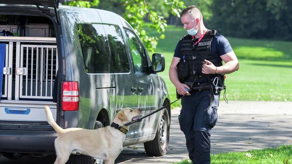 Сотрудник полиции со служебной собакой у парка Ла Грандж в Женеве