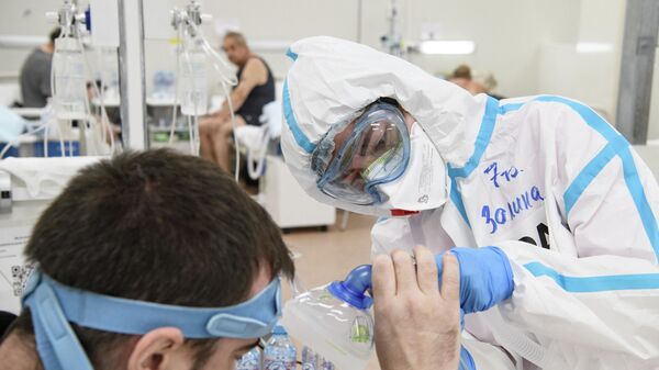 Врач оказывает помощь пациенту в резервном госпитале для лечения больных коронавирусом в автомобильном торговом центре (АТЦ) Москва