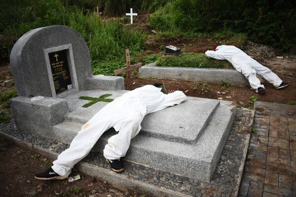 Копатели могил отдыхают на надгробиях на кладбище в Бандунге, Индонезия 
